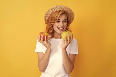 Hasır şapkalı mutlu kızıl kız elma tutuyor, detoks yapıyor..