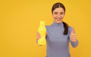 Başparmağını kaldır. Susuz kalma. Gülümseyen kadın maden suyu tutuyor. Susadım. Plastik şişeli genç kız. Sağlıklı bir yaşam tarzı. Vücuttaki su dengesi. Günde bir içki. hidrasyon canlılığı.