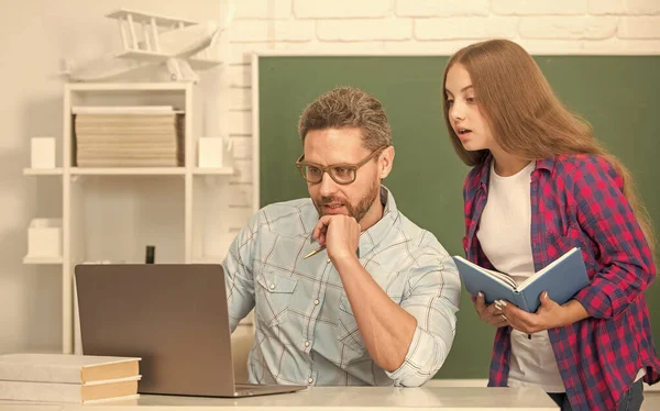 busy teen girl and teacher man in high school with workbook and pc at blackboard, education online.