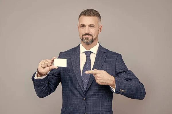 confident businessman man in suit pointing finger on business card for copy space, contact me.