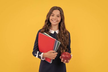 Neşeli çocuk okul kitaplarını ev ödevi için tutuyor ve sarı arka planda elmalı öğle yemeği, öğle yemeği..