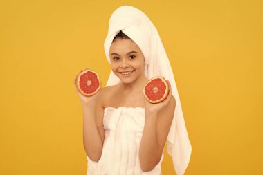 Sarı arka planda greyfurtlu havluyla mutlu çocuk..