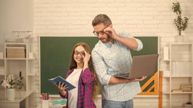 Okulda mutlu baba ve çocuk eğitimi karatahta arka planda kitap ve dizüstü bilgisayarla, okul.