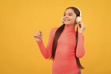 Mutlu genç kız sarı arka planda kulaklıkla müzik dinle, kopyalama alanı, dijital aygıt.