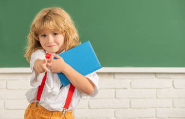 Sınıftaki mutlu genç çocuk. Okula dönüyorum. Bilgi günü. Eğitim konsepti. Tahtada uzun saçlı inek çocuk. 1 Eylül çocukluk gelişimi. Defteri olan çocuk. Boşluğu kopyala.