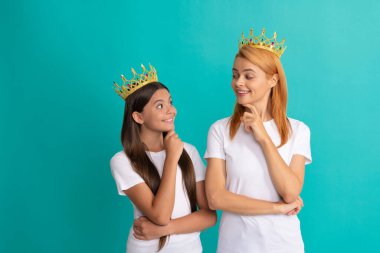 Kibirli kadın anne ve kızı birbirlerine gülümsüyorlar. Mavi taçlı, bencil..