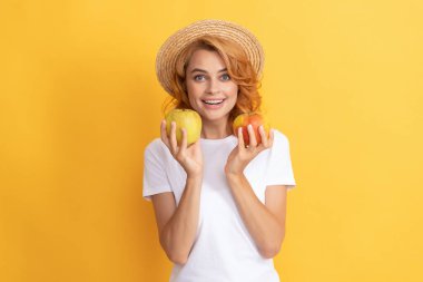 Hasır şapkalı neşeli kızıl kız elma ve vitamin tutuyor..