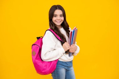 Schoolgirl, teenage student girl hold book on yellow isolated studio background. School and education concept. Back to school. Happy face, positive and smiling emotions of teenager girl
