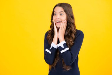 Excited face. Amazed expression, cheerful and glad. Teenager child girl with shocked facial expression. Surprised face expression, isolated on yellow background. Happy surprise
