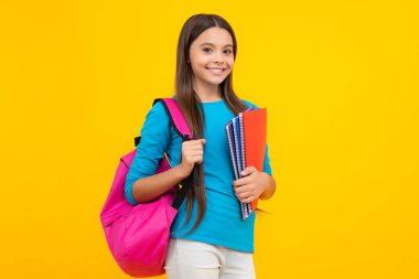 Schoolchild, teenage student girl hold book on yellow isolated studio background. School and education concept. Back to school. Happy teenager portrait. Smiling girl