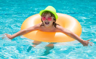 Yüzme havuzunda şişme oyuncak yüzüğü olan bir çocuk. Çocuklar yaz tatilinde yüzerler. Şamandırada çocuk için yüz. Plaj denizi ve su eğlencesi