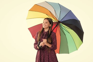 Sonbahar sezonu. Yağmurlu hava tahmini. Okula dönüyorum. Sonbahar moda aksesuarı. Şık bir genç kız. Gülümseyen çocuk renkli güneş şemsiyesi tut. Gökkuşağı şemsiyeli çocuk beyaza izole edilmiş.