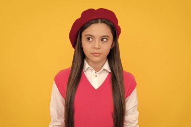 Çocuk başka tarafa bakıyor. Bereli ciddi bir çocuk. Çocuğun uzun saçları var. Deri güzelliği. Gençlik ve gençlik. Sıradan moda. Sarı arka planda Fransız bir genç kız. çocukluk mutluluğu. Okula geri dön..