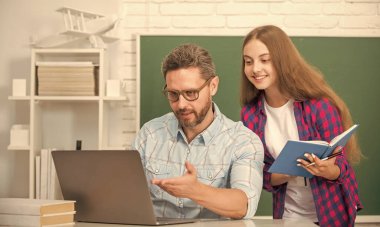 Mutlu çocuk ve baba sınıflarında kitap ve bilgisayarla karatahta oturuyorlar..