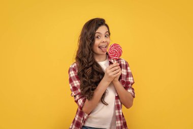 Mutlu kız lolipopu tutar. Lolipop çocuk. Uzun kıvırcık saçlı hippi çocuk lolipopu yaladı. Çubukta şeker. Karamelli şeker dükkanı. Tatlı çocukluk hayatı. Genç diş bakımı. Tatlı düşkünü. Lezzetli.