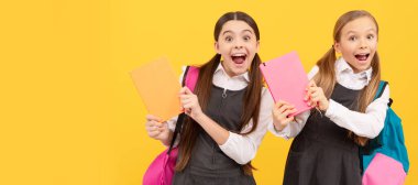 School girls friends. Happy children in formal school uniforms hold study books yellow background, knowledge day. Banner of schoolgirl student. School child pupil portrait with copy space