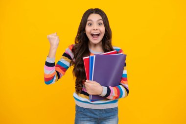 Amazed teenager. Back to school. Teenager schoolgirl with book ready to learn. School girl children on isolated yellow studio background. Excited teen girl