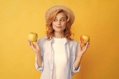Gençlik sağlığı. Doğal organik taze elma. sağlıklı bir hayat. diyet ve cilt güzelliği. Diş bakımı. Yemek molası. Detoks. Gülümseyen kız elma meyvesi seçiyor. Vitamin ve diyet. Hasır şapkalı kadın.