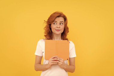 Kız kitapla çalışıyor. Özel öğretmen planlamacı. Kitap aşığı. Okula dönüyorum. Eğitim ve bilgi. Kadın okuyucu. Sarı arka planda ilham verici öğrenci.