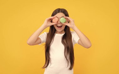 Tatlı fırınında sürpriz mutlu çocuk. Çocuk Fransız Makaronu 'nu tutuyor. Kurabiye. Şekerleme. Tatlı Fransız kekleri. Genç kız diş bakımı. Tatlı düşkünü. Lezzetli. Pastane bisküvileri.