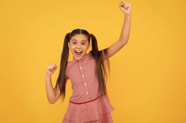Mutlu hevesli çocuk el hareketini yaparken çığlık atıyor ve sarı arka planı kutluyor, neşe.