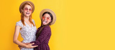 Mother and daughter kid banner, copy space, isolated background. glad mom and daughter in straw hat on yellow background
