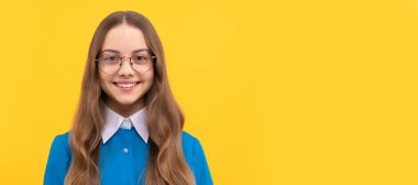 Child development and learning. Girl child in eyeglasses yellow background. Child face, horizontal poster, teenager girl isolated portrait, banner with copy space