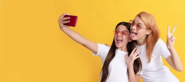 Mother and daughter child banner, copy space, isolated background. funny mom and kid making selfie on smartphone, portrait