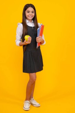 Tam boy okul çocuğu, okul çantalı genç kız izole edilmiş sarı stüdyo arka planında bir apolet tutuyor. Çocuk okulu ve eğitim konsepti