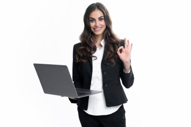 Güzel asistanın elinde defter arama bilgileri var. Dizüstü bilgisayarı olan genç bir iş kadını gri arka planda stüdyo portresini izole etti. Serbest İşçi