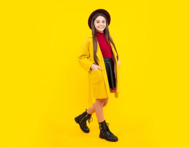 Sarı arka planda izole edilmiş rahat moda sonbahar ceketi giyen neşeli genç kız çocuğu. Mutlu ergen portresi. Kopyalama alanı oluştur