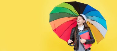 Canlı yağmur koruması. Gözlüklü mutlu kız not defteri tutuyor. Öğrenci portresi, stüdyo afişi. Okul çocuğu yüzü, boşluklar