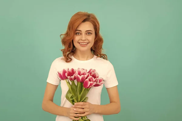 cheerful woman with tulip flower bouquet on blue background.