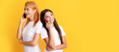 Anne ve kız çocuk afişi, kopyalama alanı, izole bir arka plan. Kadın anne ve çocuk modern akıllı telefon ve sohbet kullanarak konuşuyor.