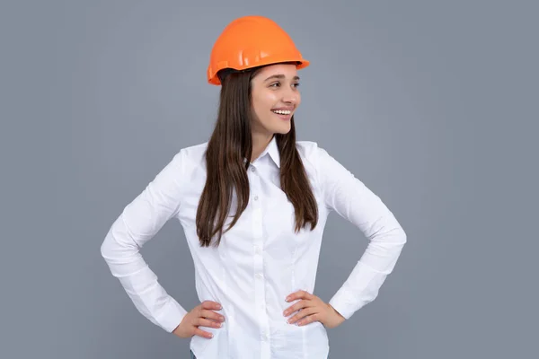 Young beautiful worker woman in helmet isolated on gray background.