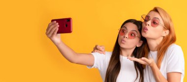 Mother and daughter child banner, copy space, isolated background. happy woman and girl take selfie with smartphone. selfie family. modern life
