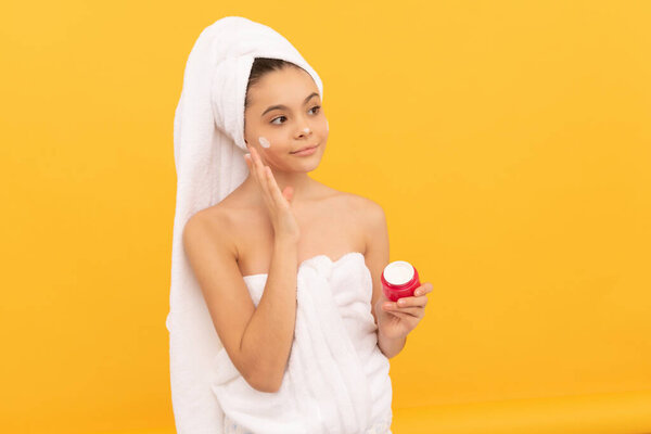 девушка-подросток улыбка в полотенце для душа нанести крем для лица.