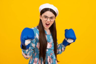 Heyecanlı bir yüz. Sarı izole edilmiş arka planda boks eldivenli genç boksör kız. Şaşırtıcı bir ifade, neşeli ve mutlu.