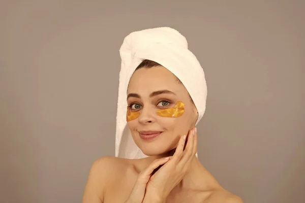 Be yourself more. beauty day in spa. applying golden anti-fatigue mask. girl reduce eye bags. skincare. facial collagen cosmetic. moisturizing skin. cosmetology. young woman in terry towel use patch.