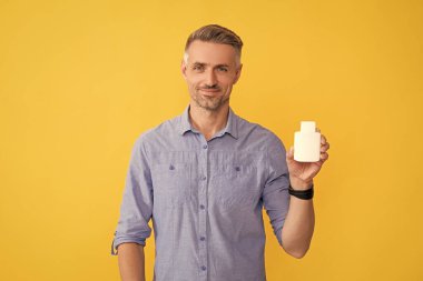 Günlük vitaminler ve takviyeler. Erkek ağrı kesici veriyor. Gülümseyen adam ilaç haplarıyla kavanozu tutuyor. Uyuşturucu işi. Adam ilaç alıyor. Tıbbi reklam. Enerji ilacı sunan adam.