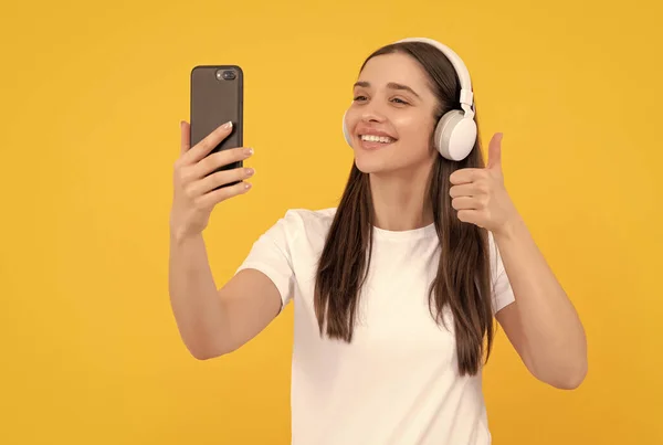 Smiling Woman Listen Music Earphones Smartphone Show Thumb Yellow Background — Stockfoto