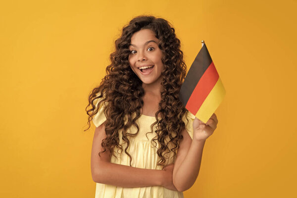 travel to germany. amazed teen girl hold german flag. schengen countries. touristic visa. education abroad for child. kid with curly hair study abroad.