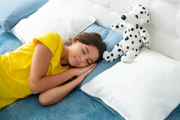 Kid lying and sleeping on bed with toy. Child teen sleeps in the bed. Sleeper, napping concept. Sleeping and dreaming kids