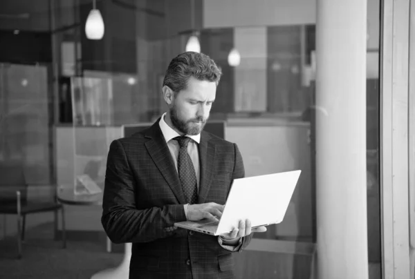 mature bearded ceo man in businesslike suit work online on wireless computer outside the office, freelancer.