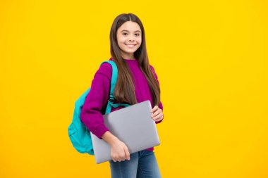 Schoolchild, teenage student girl with laptop on yellow isolated studio background. Children school and education concept