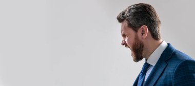 Gri arka plan fotokopi alanı diye bağıran öfkeli profesyonel adamın profil portresi, çığlık. İnsan yüzü portresi, fotokopi alanı olan pankart. Takım elbiseli bir iş adamı, izole stüdyo geçmişi var.