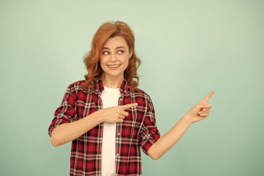 Mavi arka planda kareli tişörtlü, neşeli kızıl saçlı kadın..