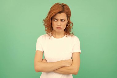 Mavi arka planda kızıl saçlı kadının portresi. Olumsuz duygularını ifade et. Kıvırcık saçlı üzgün kadın. Güzellik ve moda. Kadın manken. Genç mutsuz bir kızın güzel görünüşü..