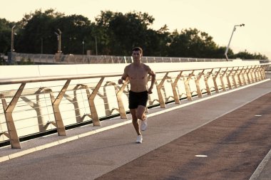 Kaslı gövdesiyle koşan atletik bir adam..