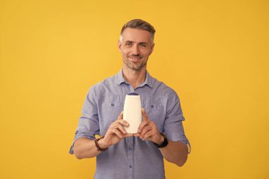 Sarı arka planda saç şampuanı gösteren adam, kozmetik..